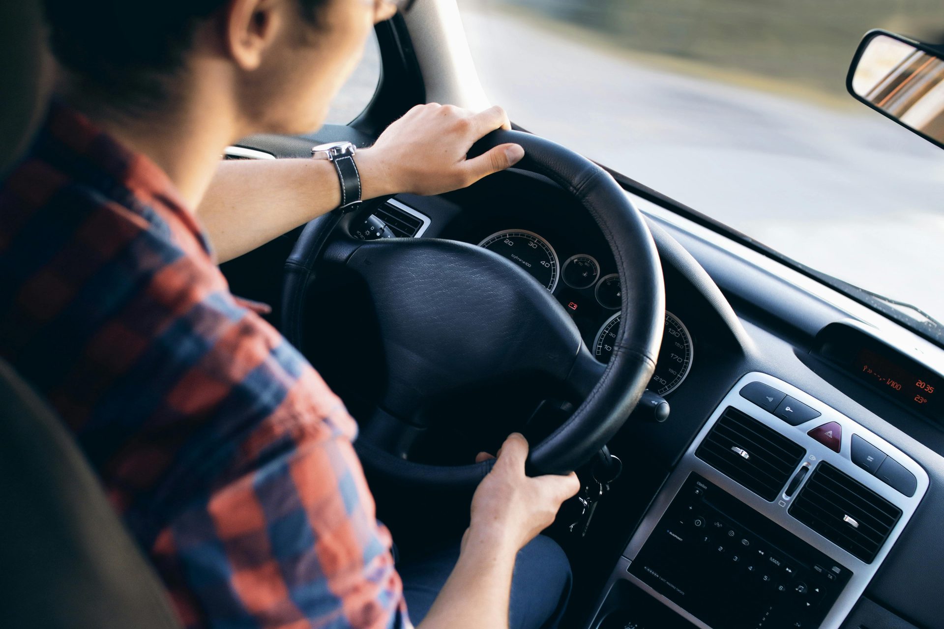 Nahaufnahme eines Mannes, der ein modernes Auto fährt. Details zum Armaturenbrett und zur Lenkung sind zu sehen.